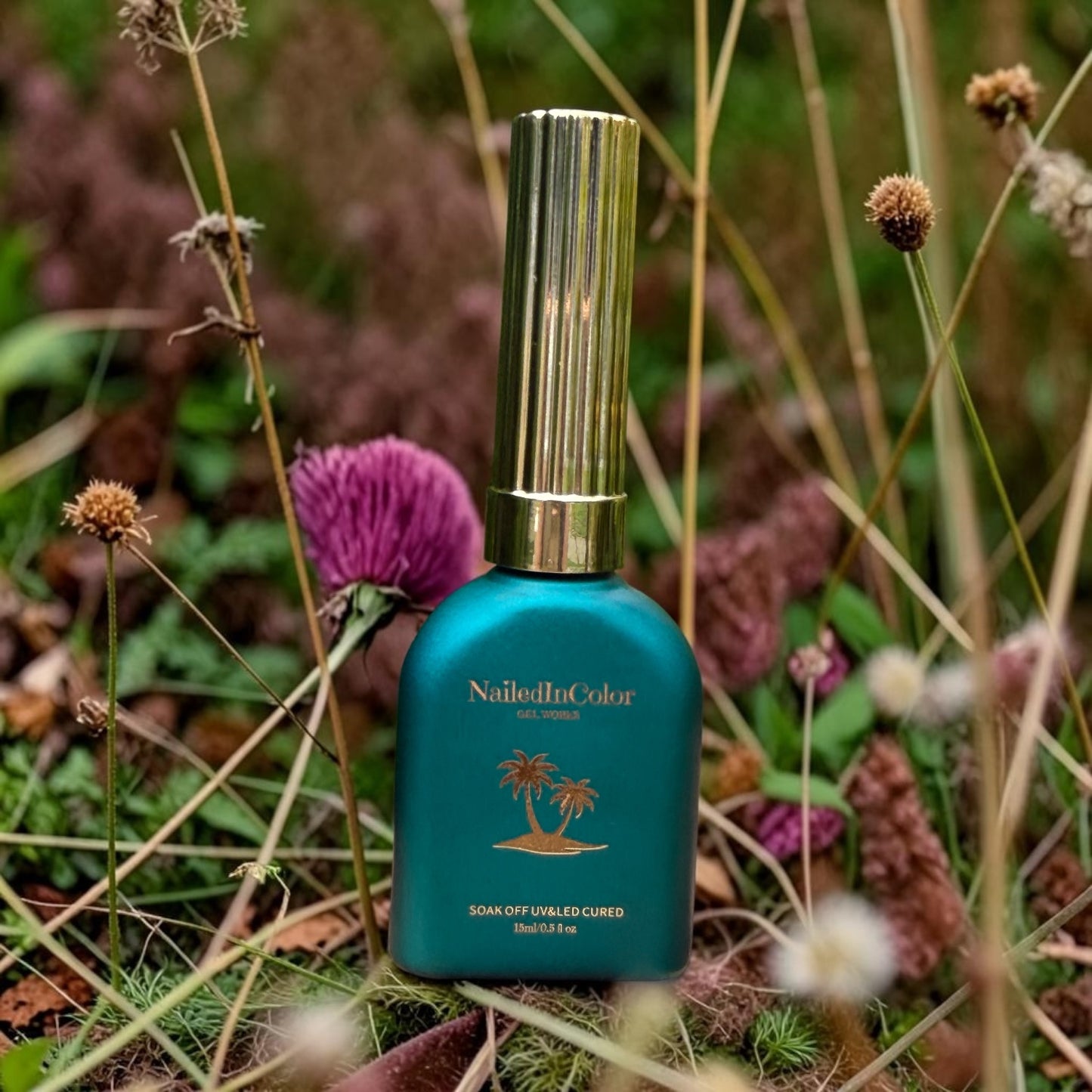 Green nail polish bottle with gold cap on a natural background with flowers and plants