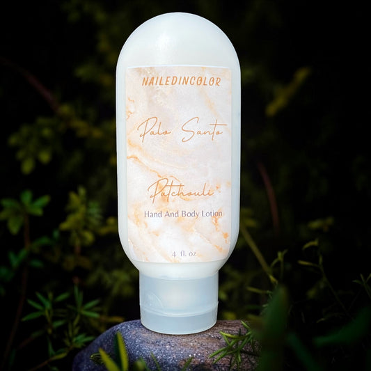A bottle of Nailed In Color 'Palo Santo' 'Patchouli' hand and body lotion stands on a small stone against a dark, blurred garden background.