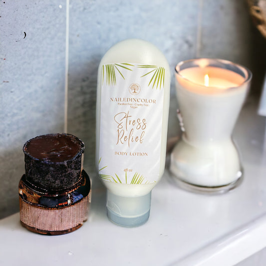 A bottle of NailedinColor Stress Relief Body Lotion stands on a white surface next to a lit candle and a small dark jar, against a gray tiled wall.