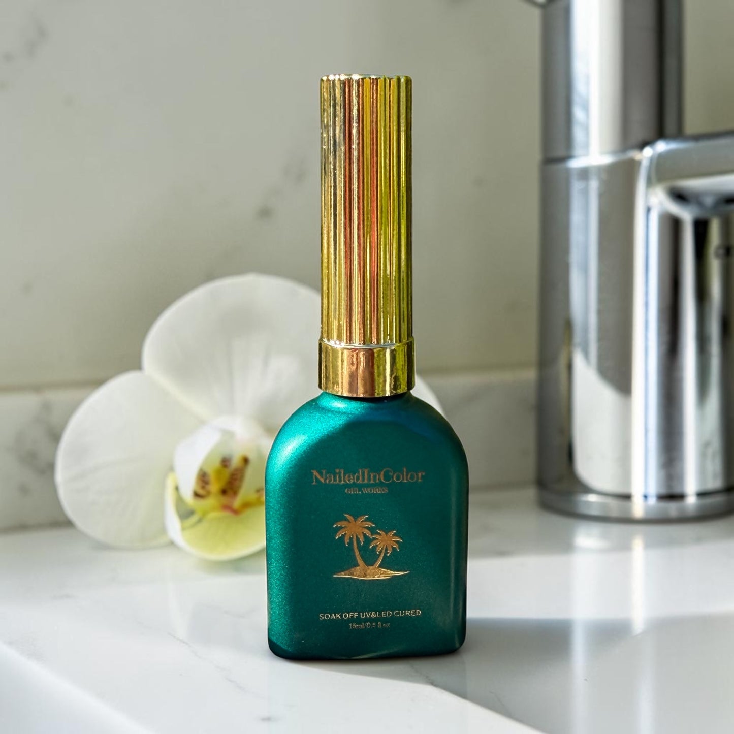 Green gel polish bottle on a white counter with a white flower in bakground and silver can