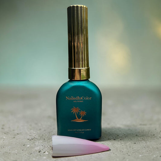 Satin green gel polish bottle with gold cap on a granite top and pale green background. nail swatch of white and pale pink