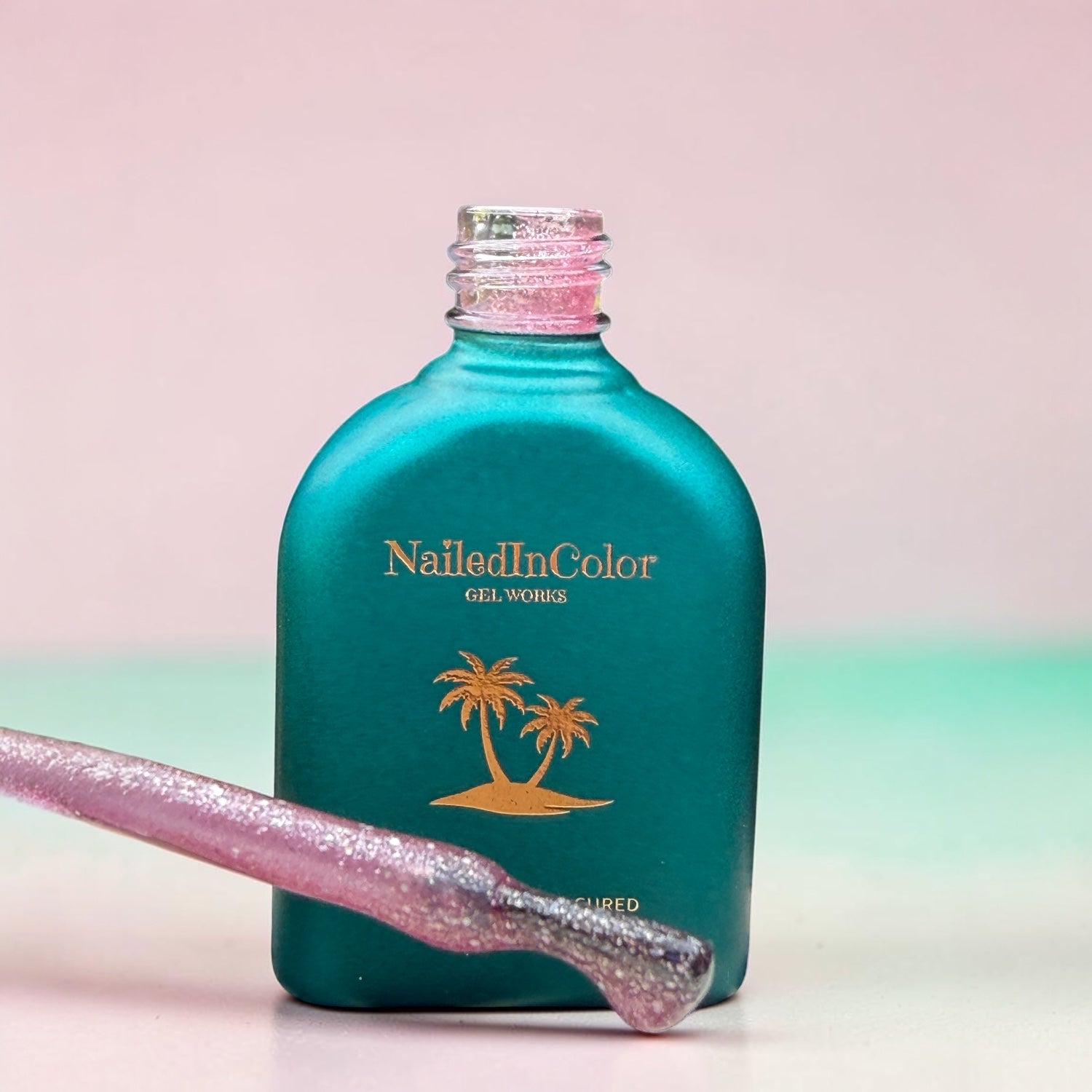 Teal bottle of NailedInColor gel with a lavender  applicator sample on a gradient background