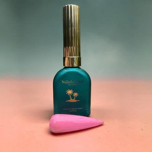 Teal nail polish bottle with gold cap on a peach and green surface, pink nail swatch with clear gel topcoat