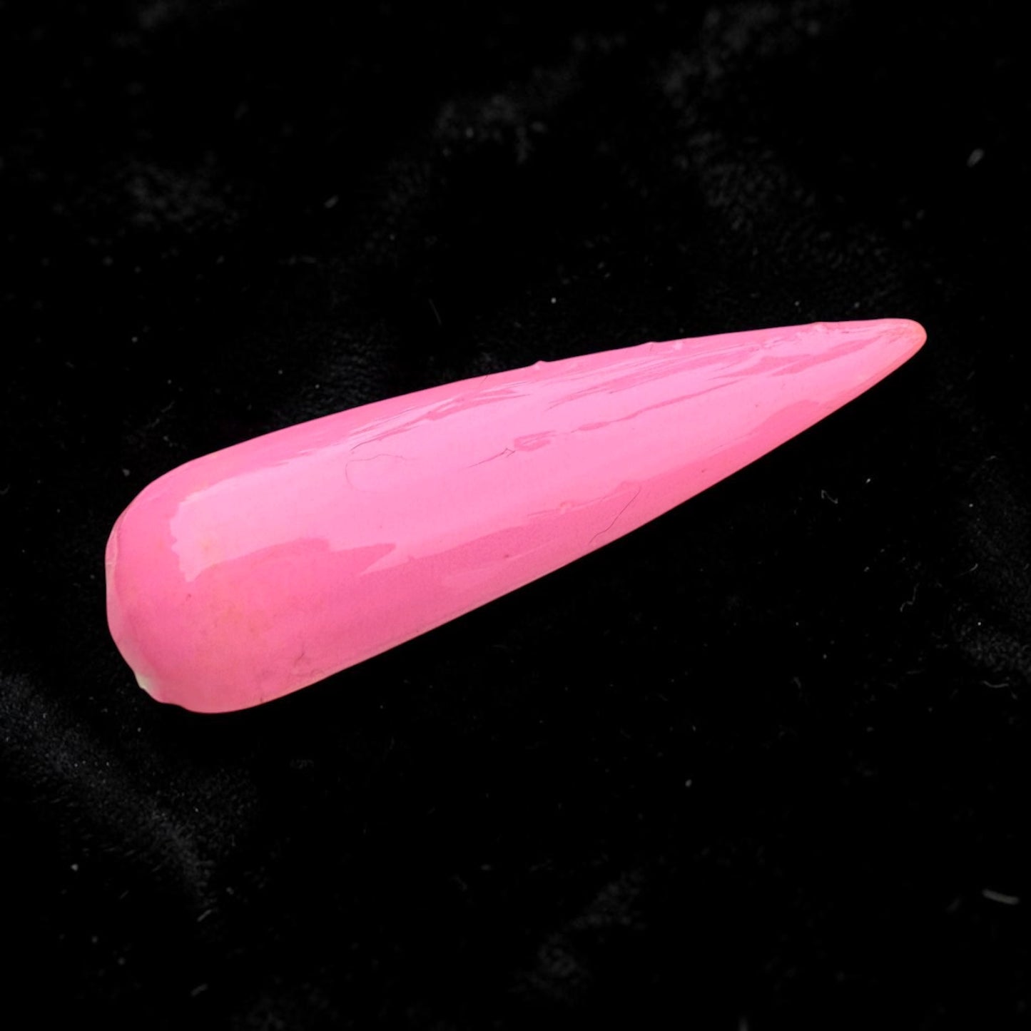Pink glossy nail swatch with topcoat on a black background
