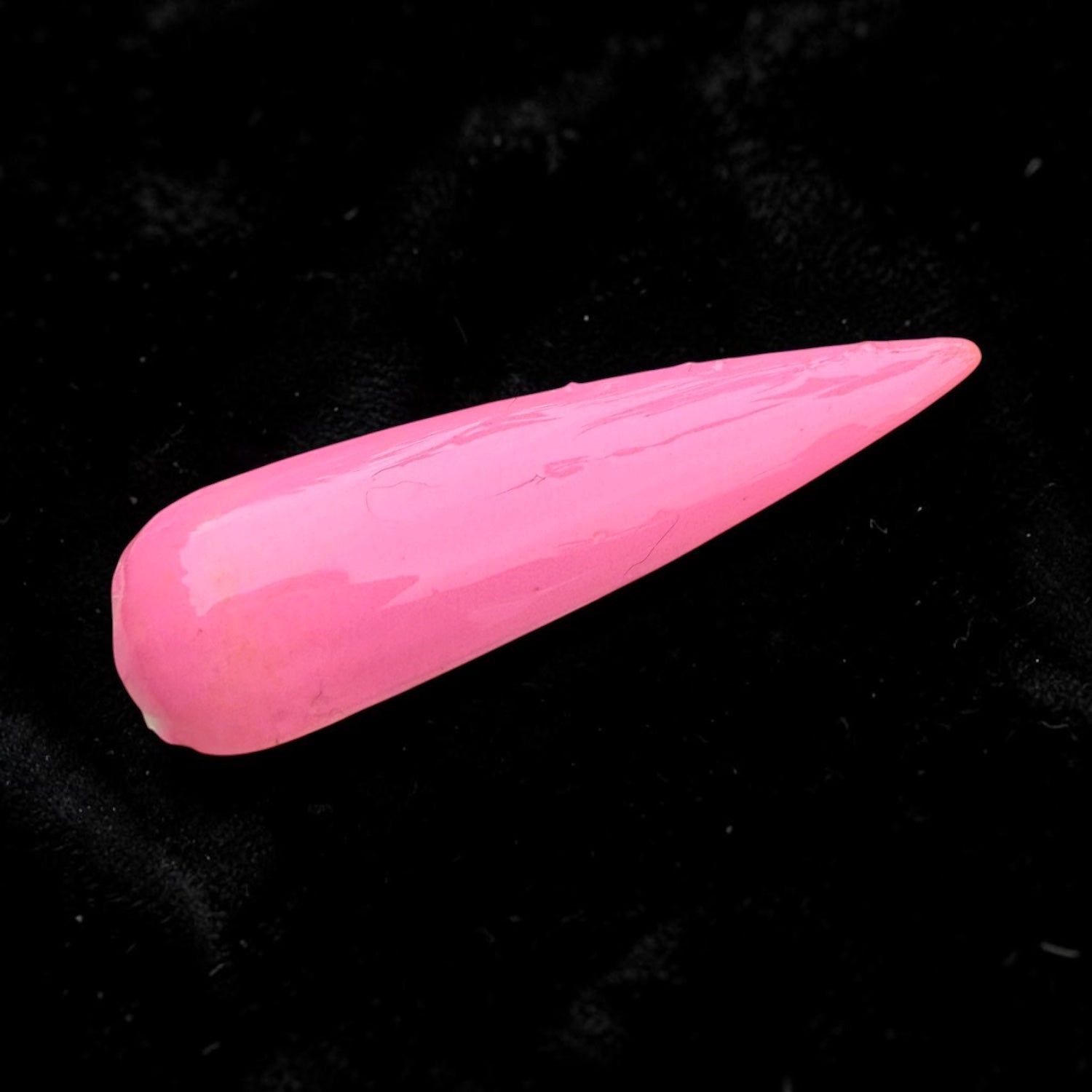 Pink glossy nail swatch with topcoat on a black background