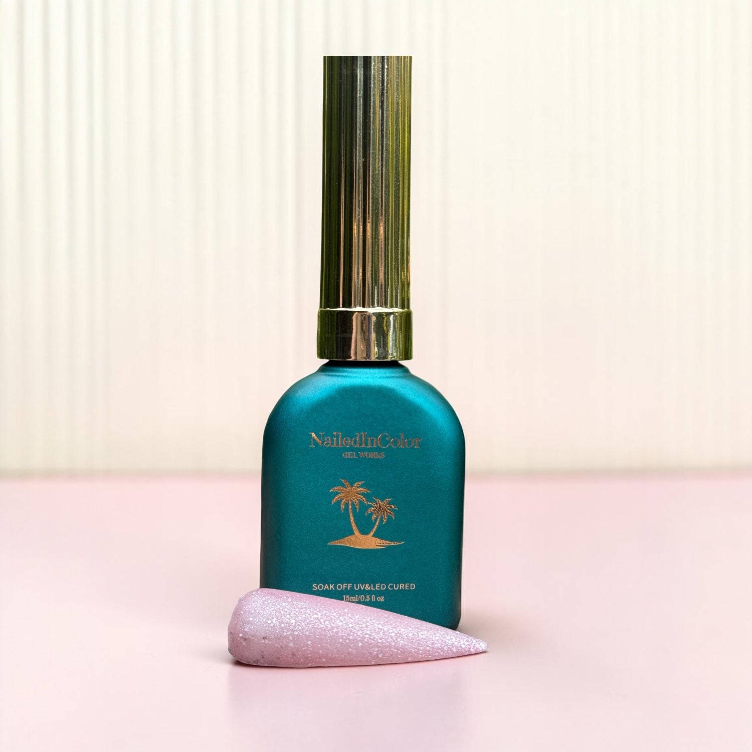 Teal nail polish bottle with gold cap on a light pink background with a swatch for a matte gel topcoat