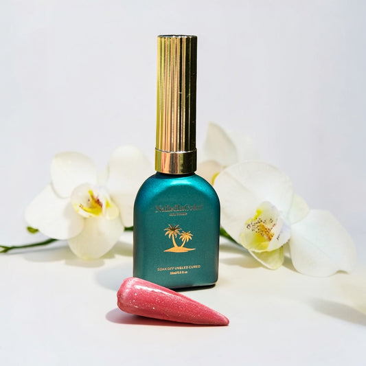 light red cat eye gel polish swatch with a green gel polish bottle in front of white flowers and background