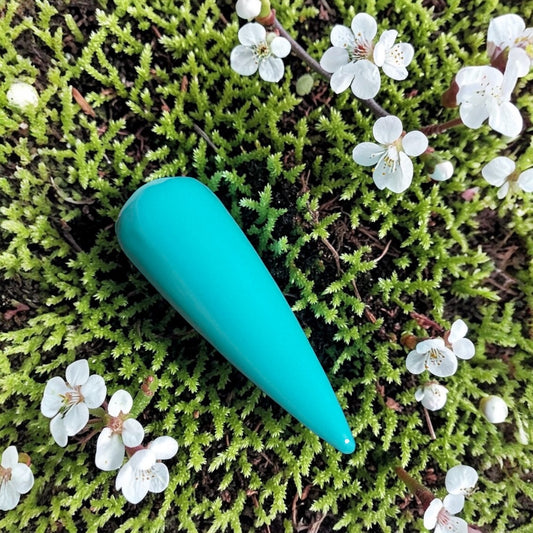 Blue green polished nail swatch on a moss bed and tiny white flowers