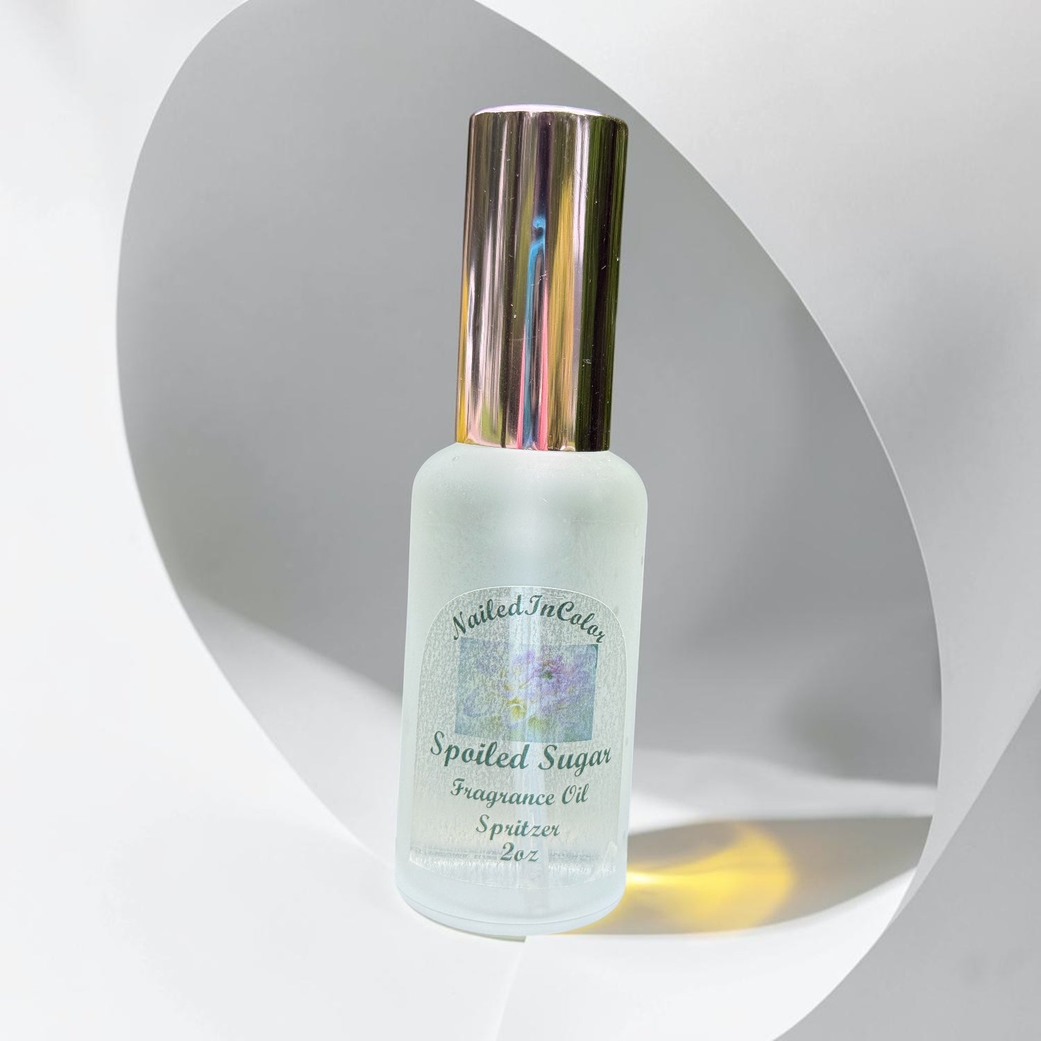 Fragrance oil spritzer bottle labeled 'Spoiled Sugar' on a light gray background with an oval like window