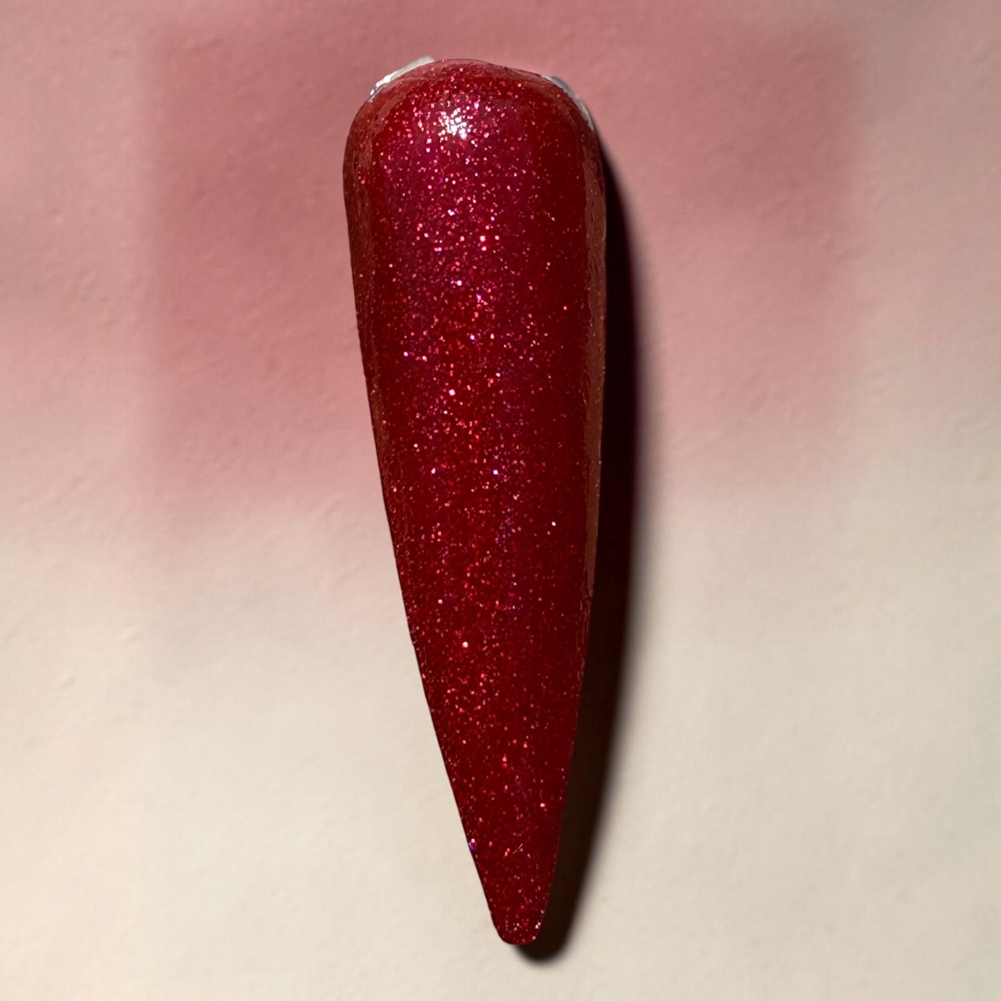 Red glittery nail polish on a light pink background