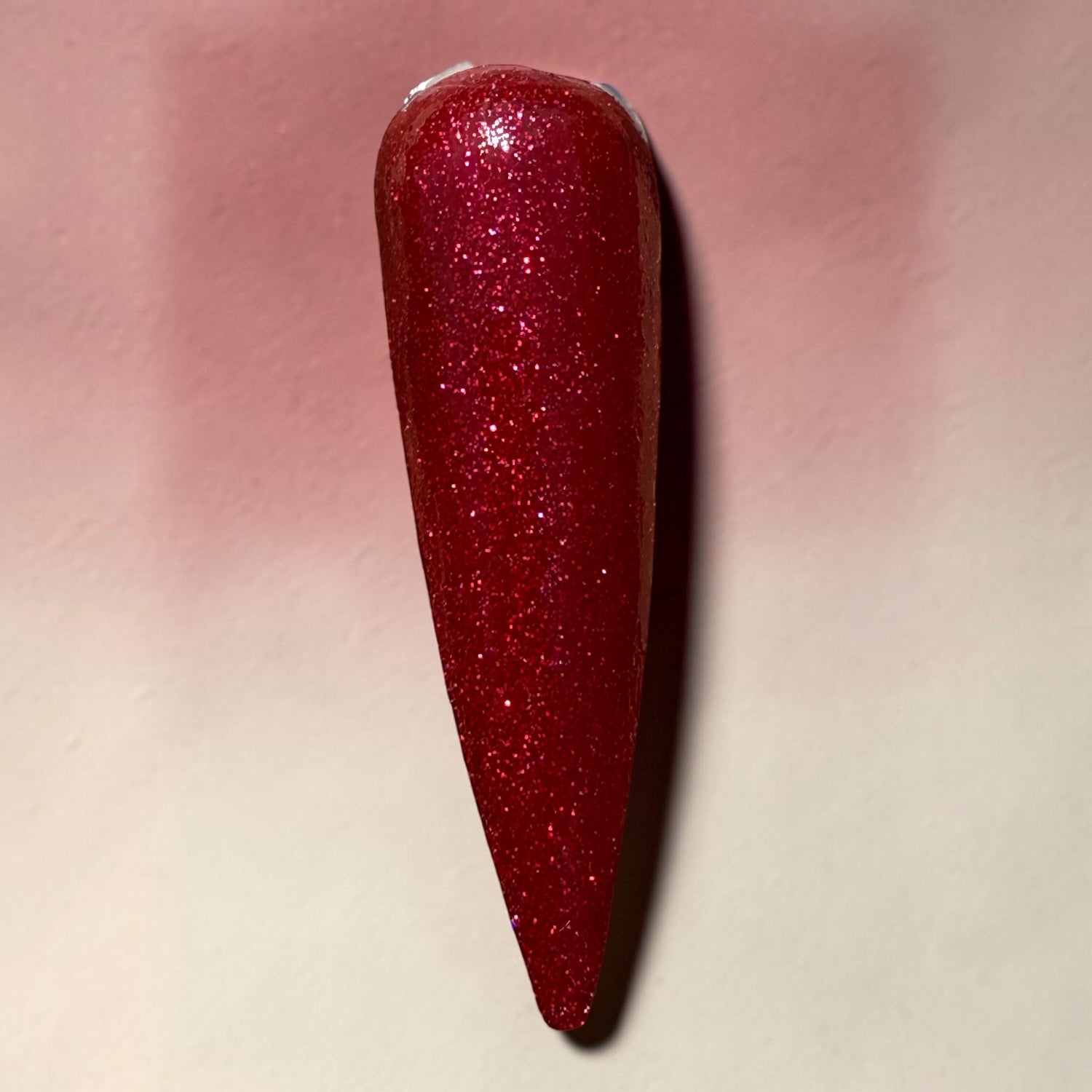 Red glittery nail polish on a light pink background