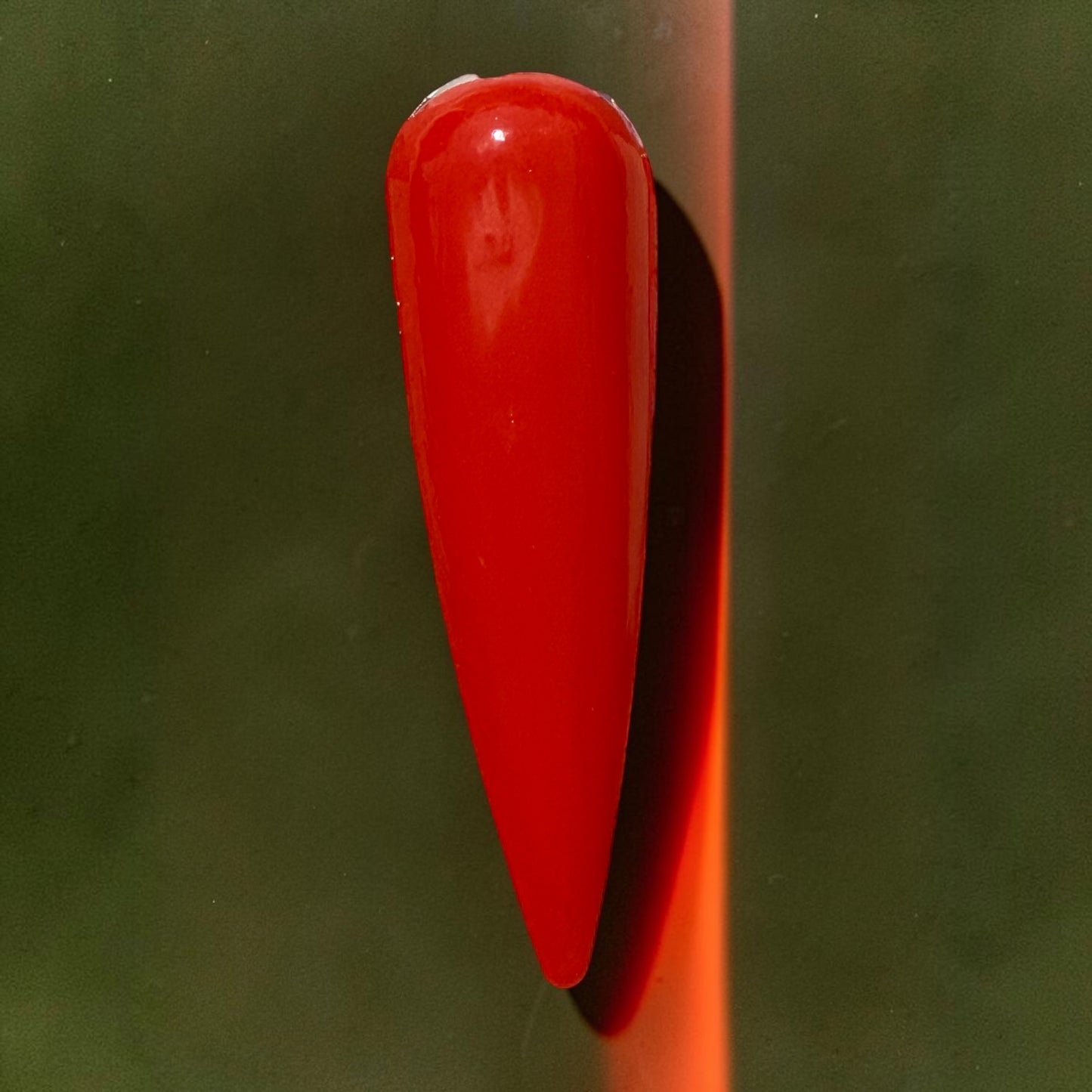 Coral orange nail tip on a green background with orange stripe
