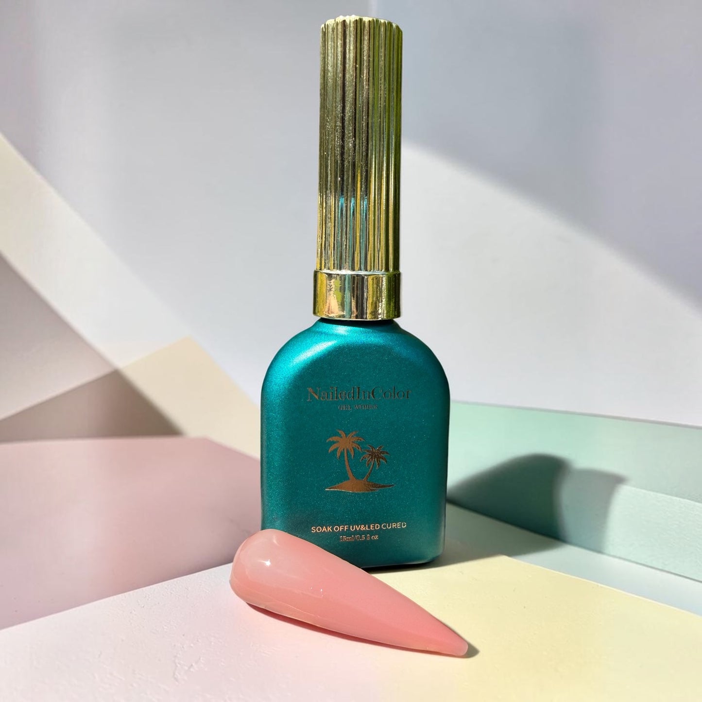 Nail polish bottle with gold cap on a pastel background with a light pink nail tip in builder gel