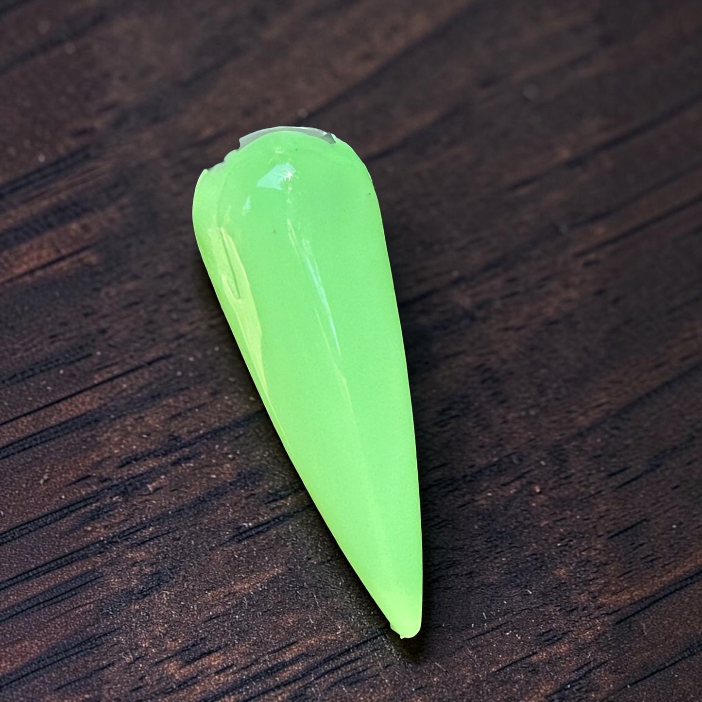 a green nail tip on dark wood