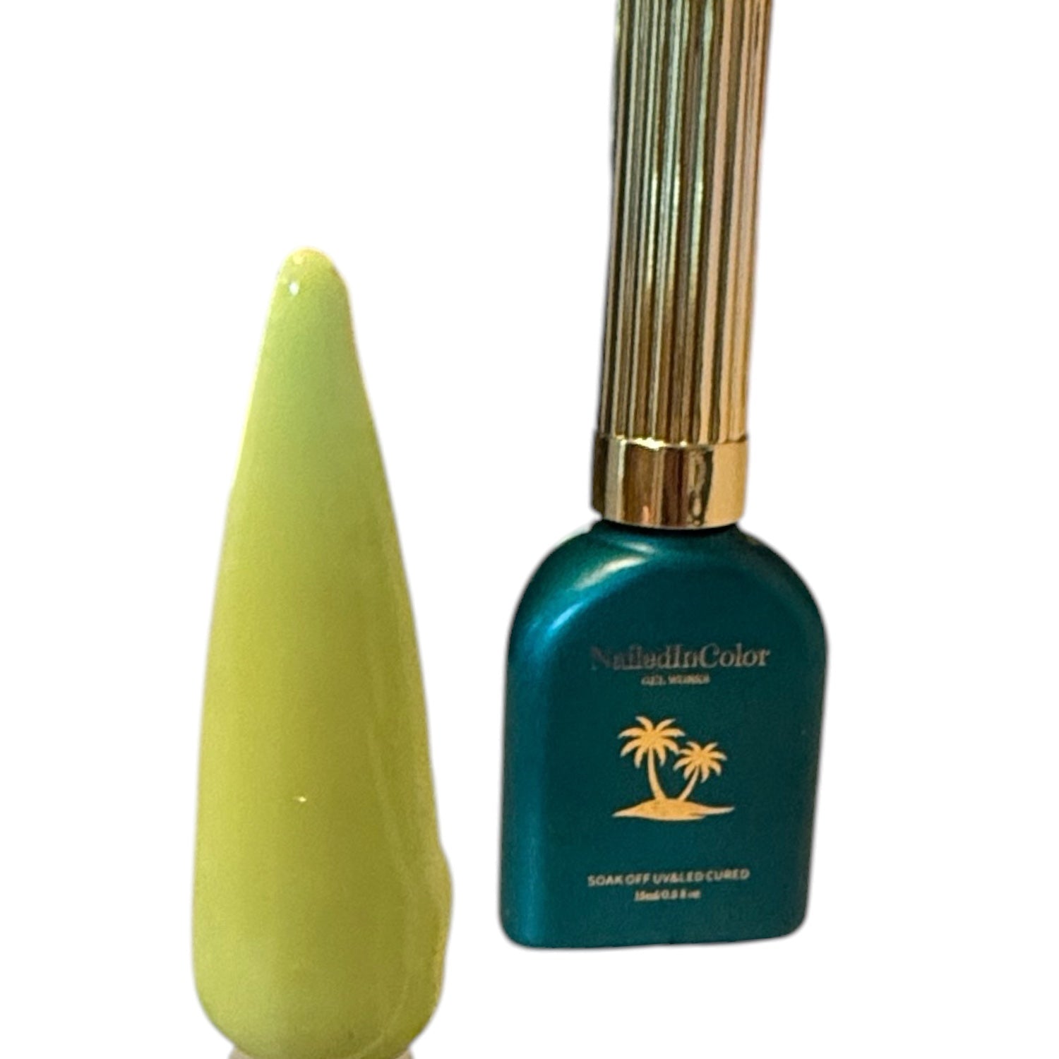 Yellow gel polished nail tip next to a green polish botte with a gold cap and a white background