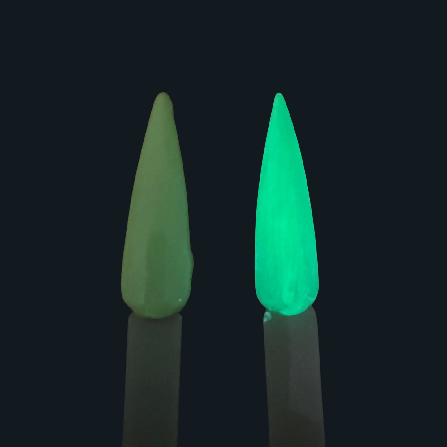 Yellow gel polish nail tip and a glow in the dark green nail tip side by side with a black background