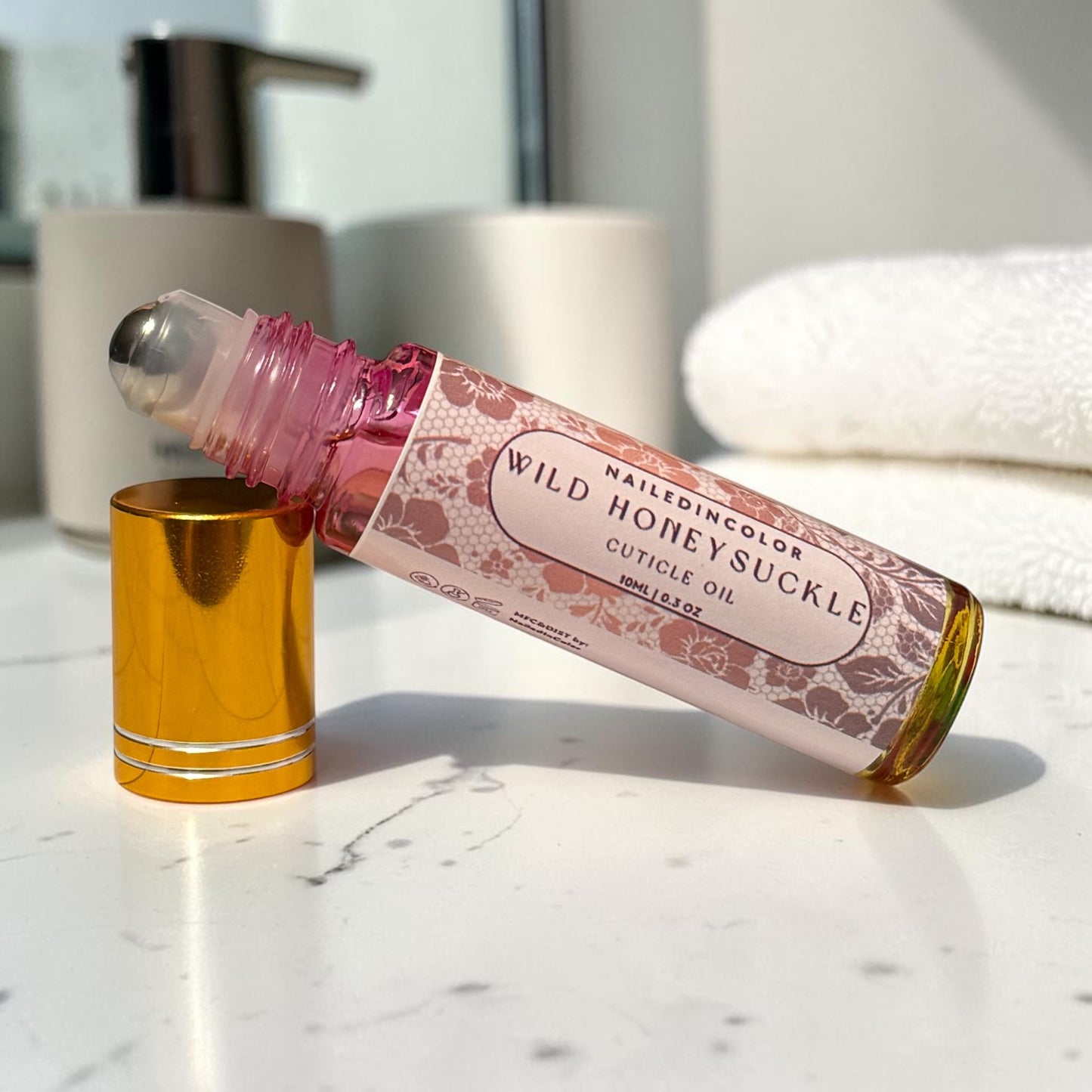 bottle of cuticle oil resting on side propped on cap. counter with towels