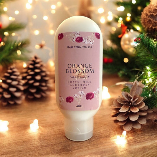 a bottle of orange blossom cashmere lotion on a wooden counter with pine cones and lights in background