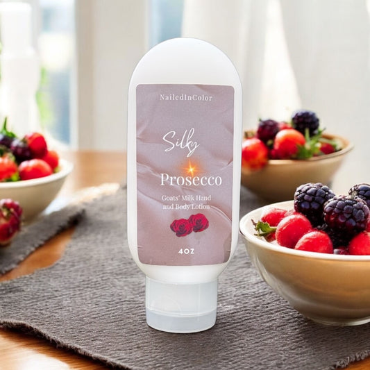 A bottle of Silky Prosecco goats' milk hand and body lotion standing on a wooden table with a placemat and bowls of fruit